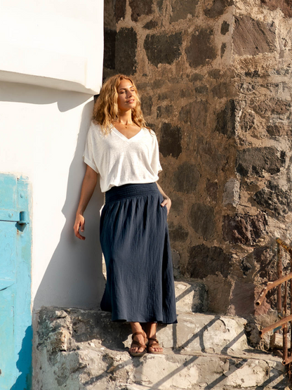 Woman wearing a white linen top and black cotton skirt.
