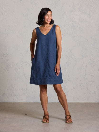 Woman wearing a blue dress standing against a plain background