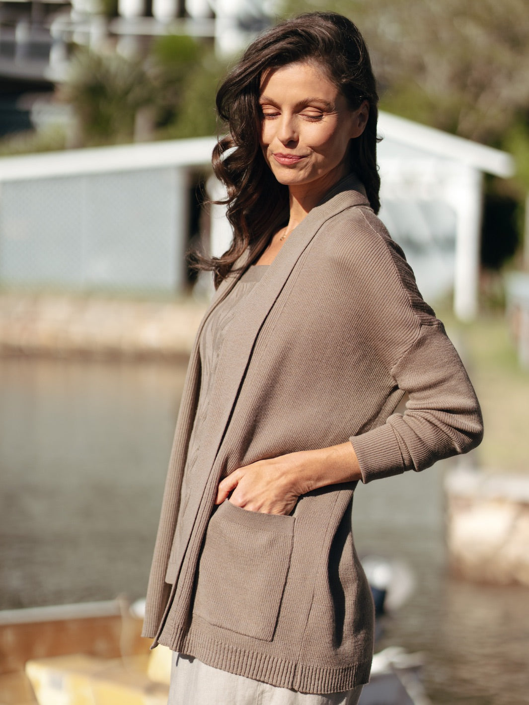 Woman wearing a brown cardigan by a waterfront
