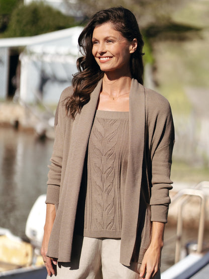 Woman wearing a brown cardigan and sweater by a body of water