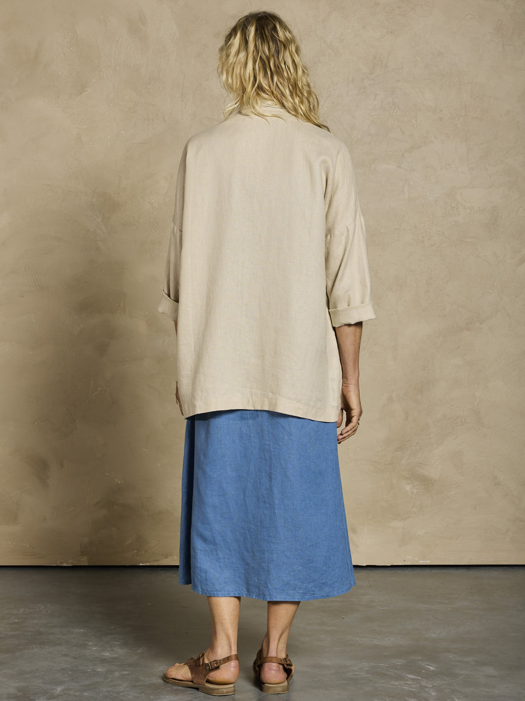 Woman in a blue linen dress and beige linen jacket.