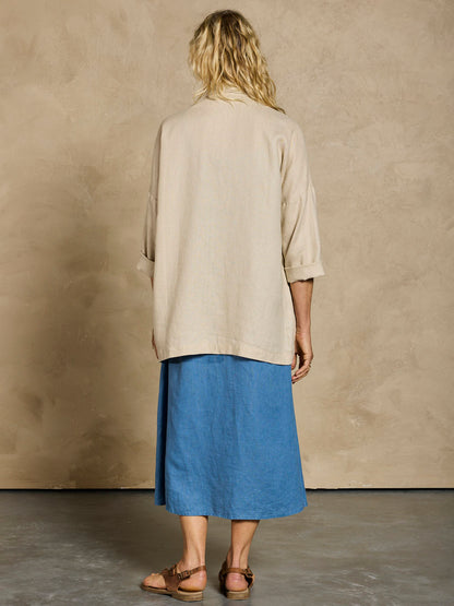 Woman in a blue linen dress and beige linen jacket.