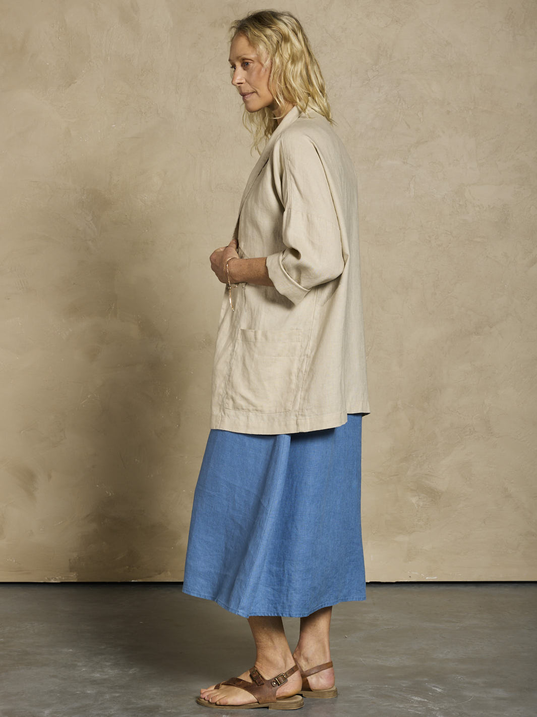 Woman in a blue linen dress and beige linen jacket.