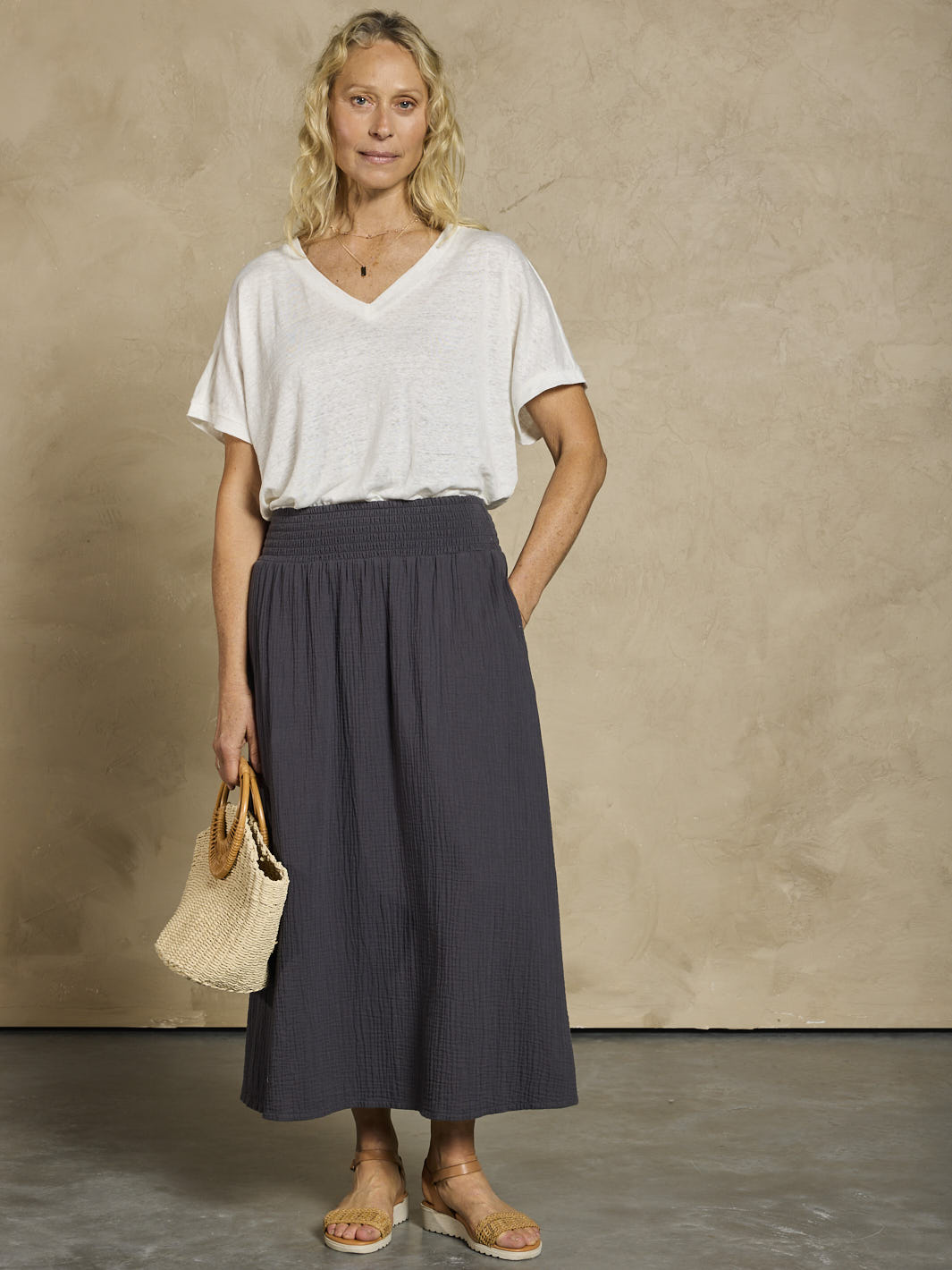 Woman wearing a white linen top and black cotton skirt.
