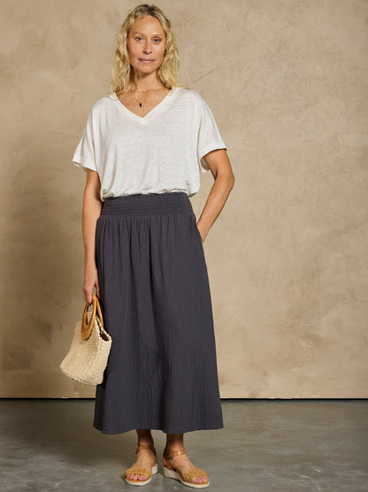 Woman wearing a white linen top and black cotton skirt.
