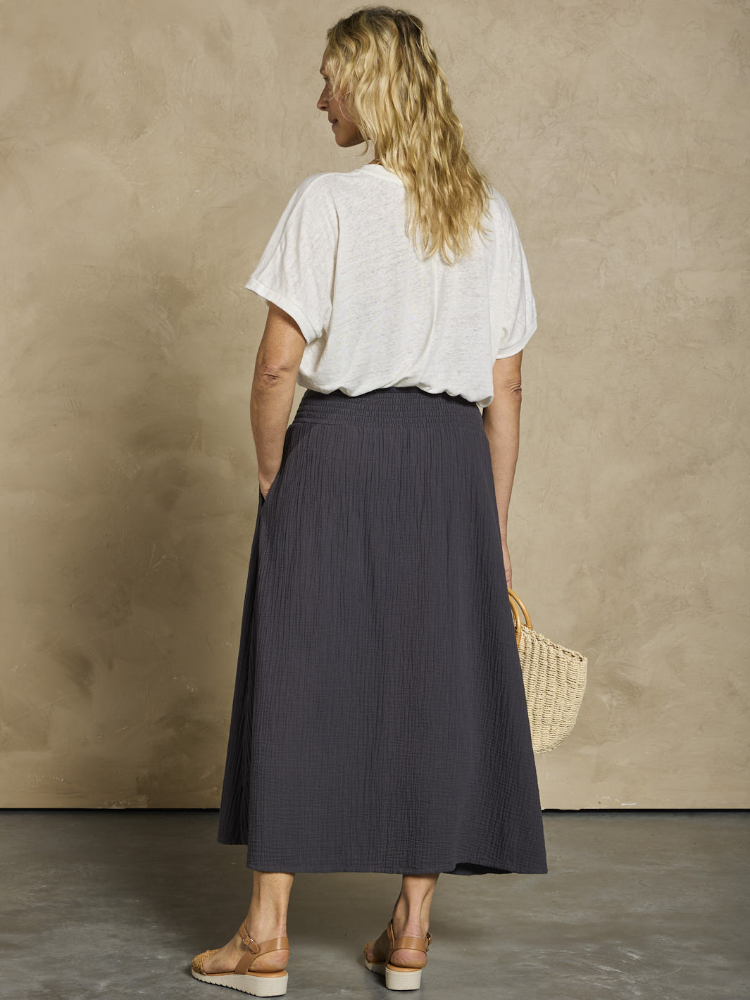 Woman wearing a white linen top and black cotton skirt.