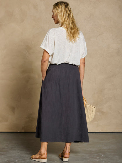 Woman wearing a white linen top and black cotton skirt.