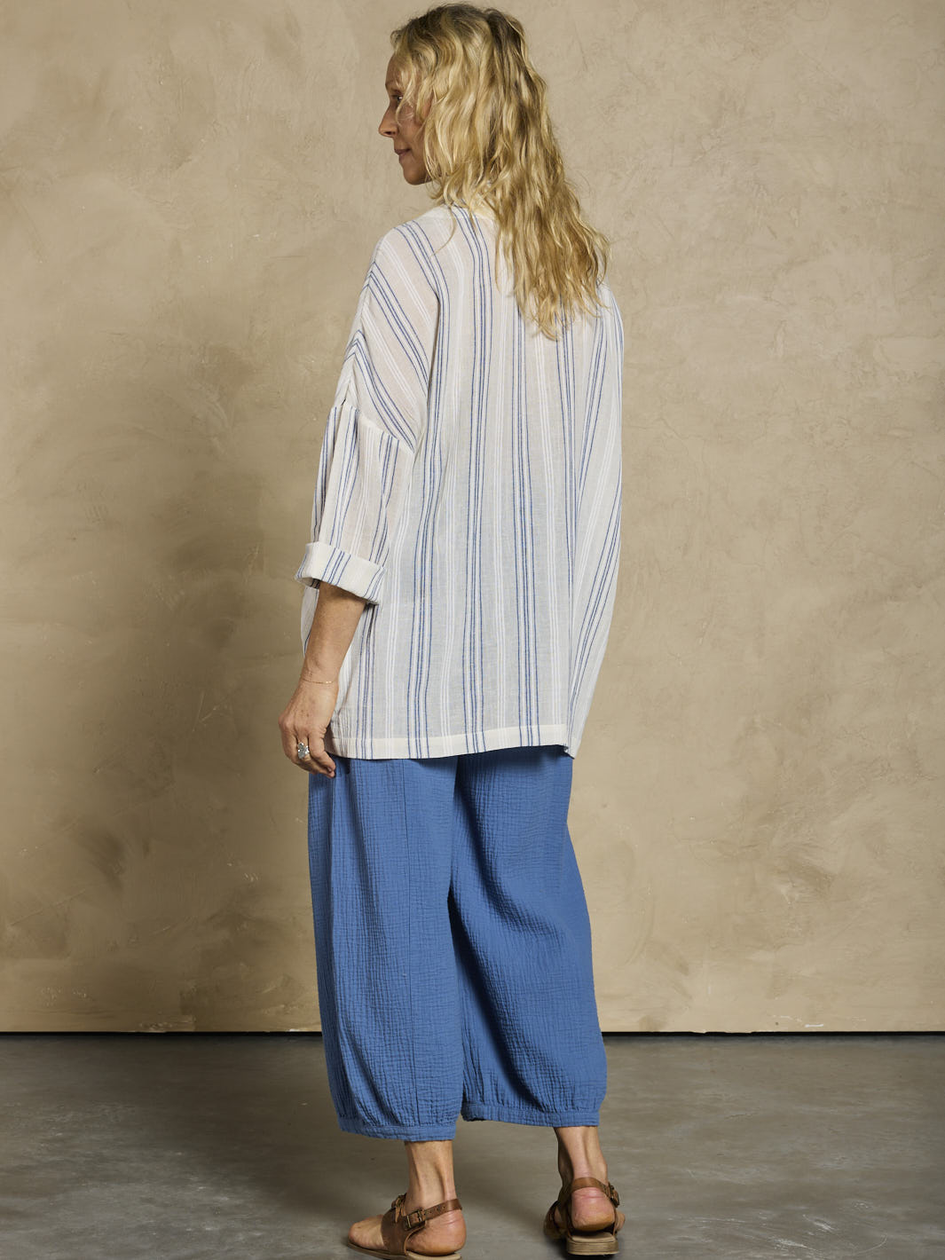 Woman wearing a white and blue cotton jacket and blue cotton pants.