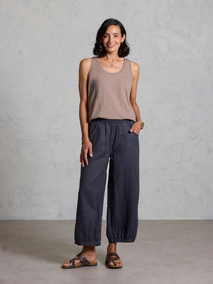 Woman wearing a sleeveless top and wide-leg pants against a plain background